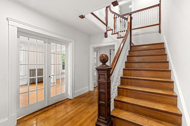 staircase with french doors, wood finished floors, ornamental molding, and baseboards
