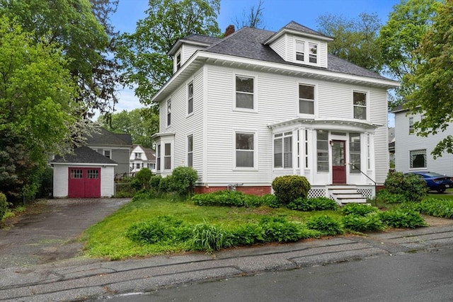 american foursquare style home with an outbuilding, entry steps, a chimney, a storage shed, and a shingled roof