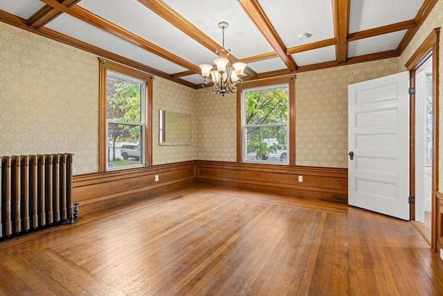 empty room with radiator heating unit, hardwood / wood-style flooring, a chandelier, coffered ceiling, and beam ceiling