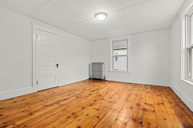 spare room featuring radiator, light wood-style floors, and baseboards