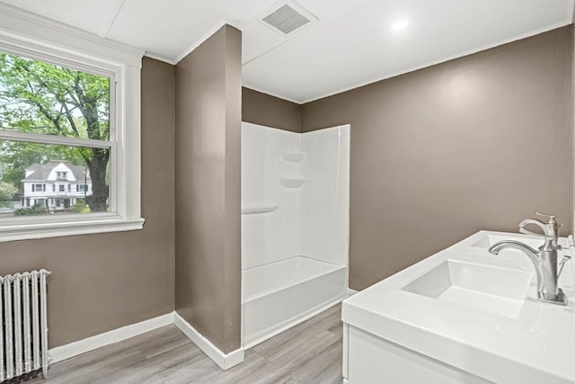 full bath with radiator, wood finished floors, baseboards, and bathtub / shower combination