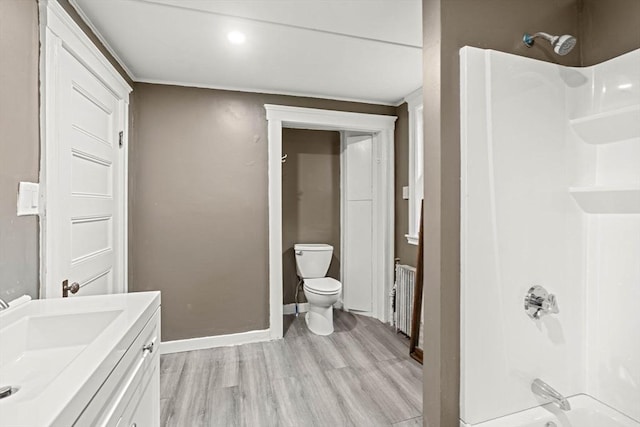 full bath featuring wood finished floors, baseboards, radiator heating unit, toilet, and vanity