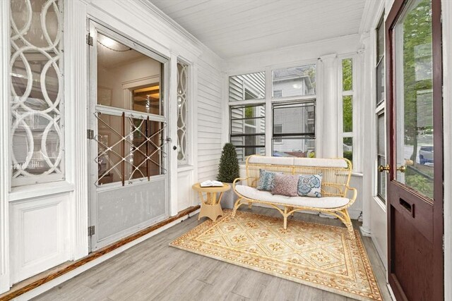 sunroom / solarium featuring wood finished floors and ornamental molding