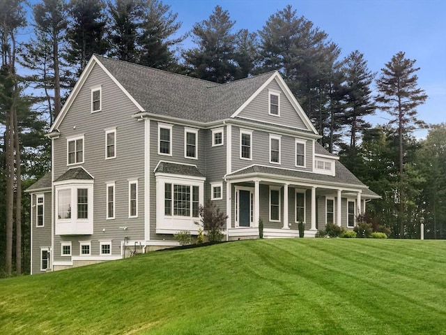 view of front of property with a front lawn, covered porch, and a shingled roof