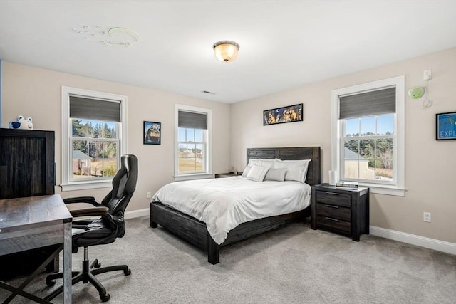 bedroom with multiple windows, light colored carpet, and baseboards