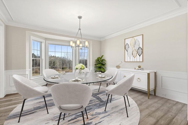 dining room with an inviting chandelier, light wood-style flooring, and a wainscoted wall