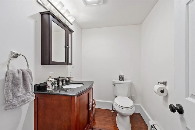 bathroom with baseboard heating, wood-type flooring, vanity, and toilet