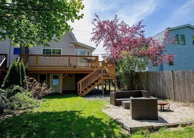 back of property with a yard, a deck, and an outdoor living space with a fire pit