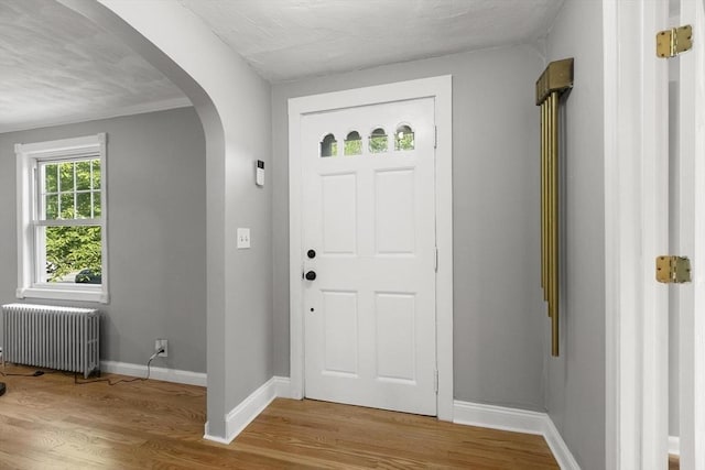 235 Groton Rd, Chelmsford, MA 01863 - foyer featuring radiator heating unit, arched walkways, wood finished floors, and baseboards