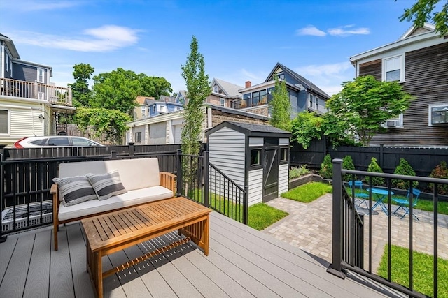 wooden deck with an outdoor living space, a storage shed, and a patio area