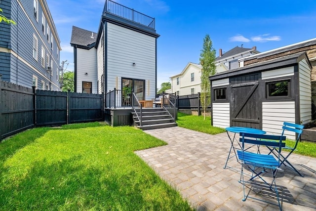 back of property with a wooden deck, a yard, a patio, and a storage unit