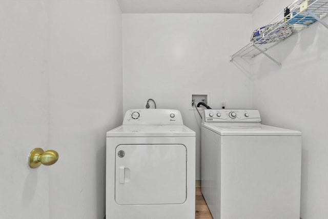 clothes washing area with wood-type flooring and washer and clothes dryer