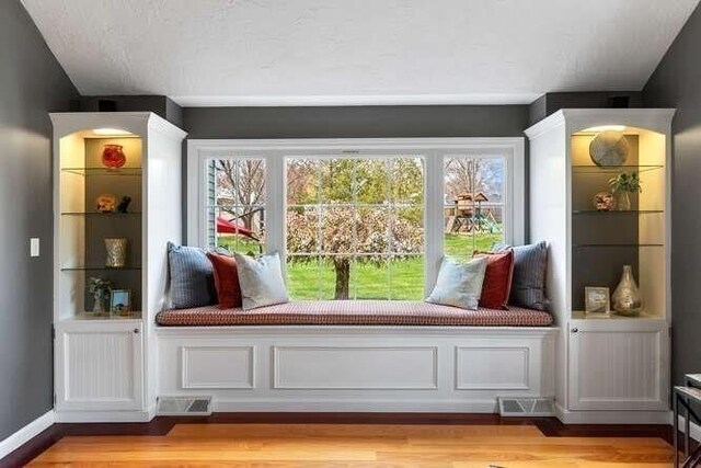 mudroom with light wood finished floors, vaulted ceiling, and a textured ceiling