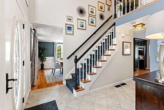 stairway with a high ceiling, baseboards, and tile patterned flooring