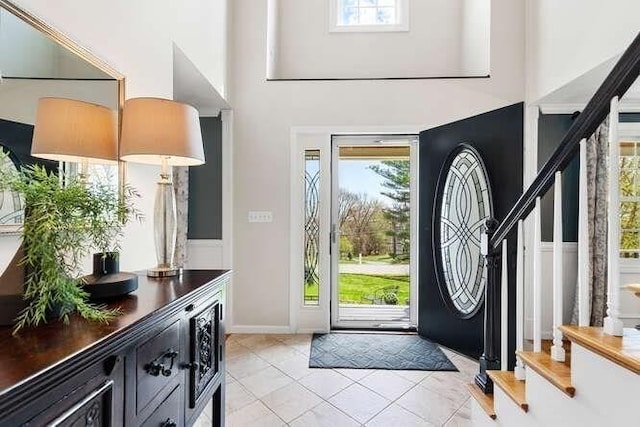 entryway featuring a high ceiling, light tile patterned flooring, and baseboards