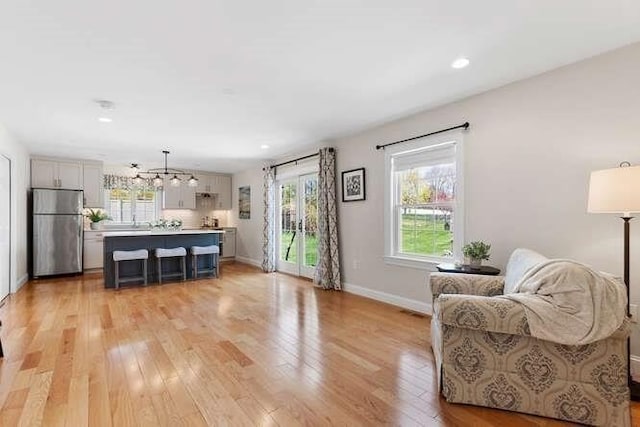 living area featuring light wood-type flooring, a chandelier, baseboards, and recessed lighting