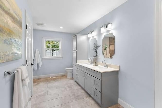 full bathroom featuring toilet, double vanity, and baseboards