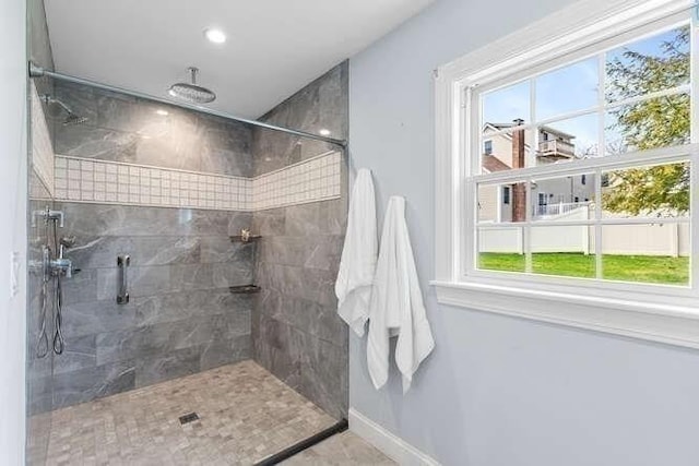 full bathroom with healthy amount of natural light, tiled shower, baseboards, and recessed lighting