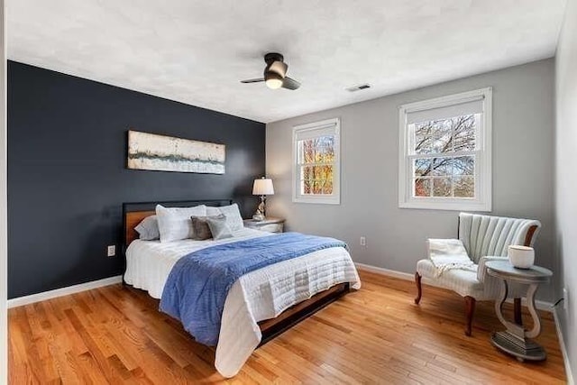 bedroom featuring baseboards, light wood finished floors, and a ceiling fan