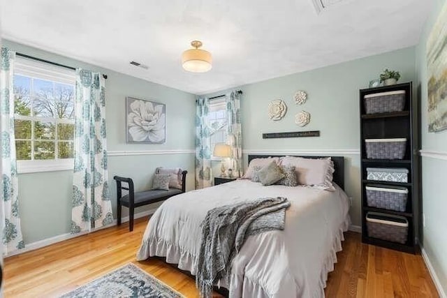 bedroom featuring multiple windows, wood finished floors, and baseboards