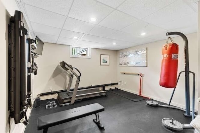 exercise area featuring a paneled ceiling and baseboards