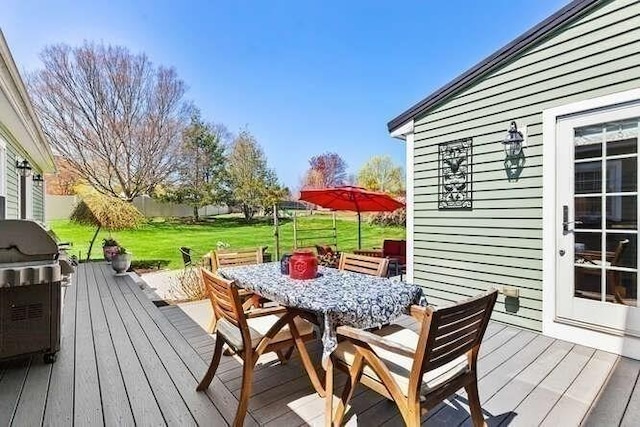 deck with outdoor dining area, a lawn, and area for grilling