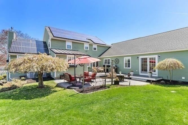rear view of property featuring solar panels, a patio area, and a lawn