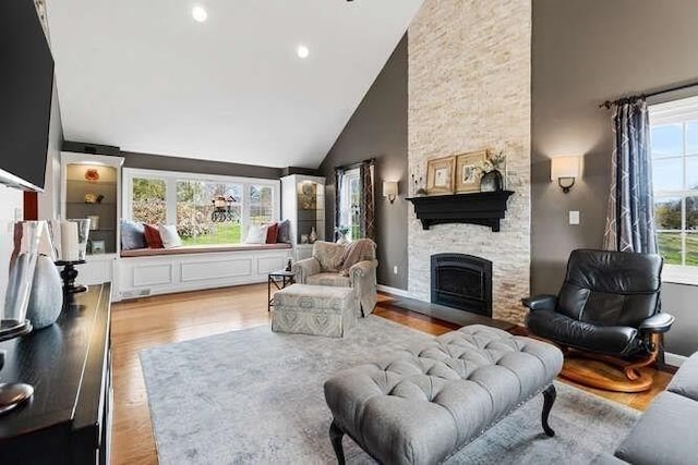 living room with high vaulted ceiling, wood finished floors, a fireplace, and recessed lighting
