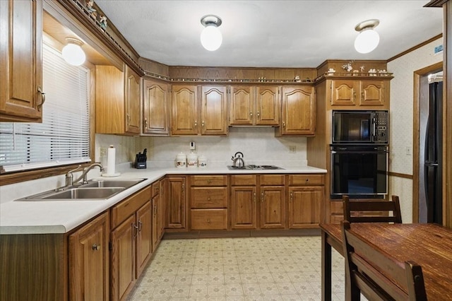 kitchen featuring brown cabinetry, light floors, light countertops, a sink, and black appliances