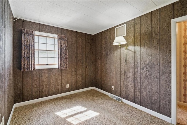 carpeted empty room with wooden walls and visible vents