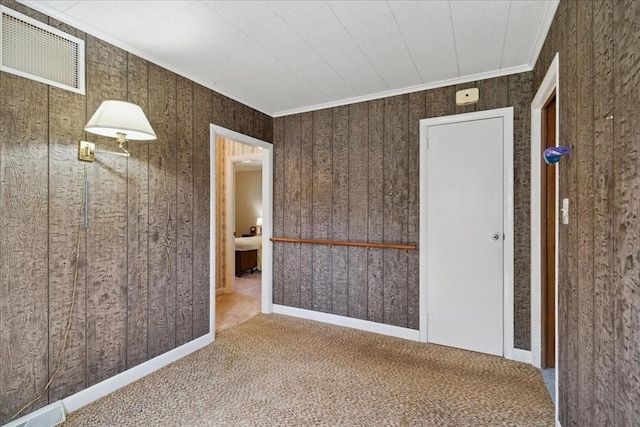 carpeted spare room with wooden walls and visible vents
