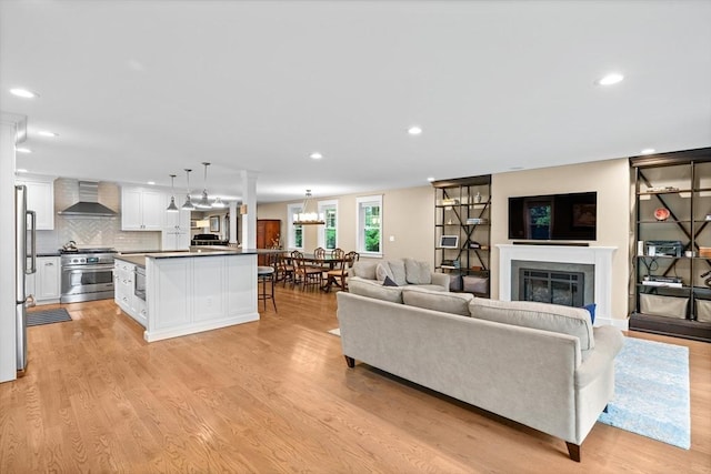 26 Downing Rd, Lexington, MA 02421 - living room featuring recessed lighting, light wood-style floors, a glass covered fireplace, and a chandelier