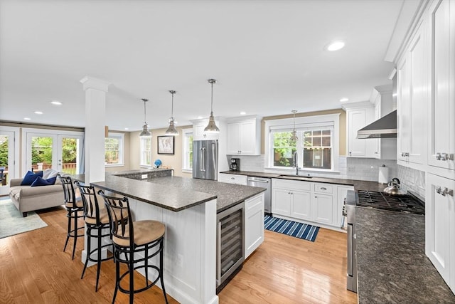 26 Downing Rd, Lexington, MA 02421 - kitchen featuring wine cooler, stainless steel appliances, a sink, wall chimney exhaust hood, and light wood-style flooring