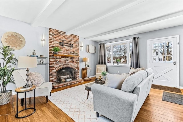 living room with a brick fireplace, hardwood / wood-style floors, and beam ceiling