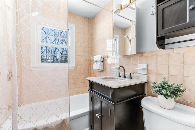 full bathroom featuring tile walls, vanity, toilet, and tiled shower / bath