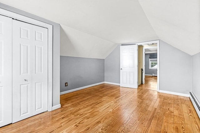 additional living space featuring lofted ceiling, a baseboard radiator, and light wood-type flooring