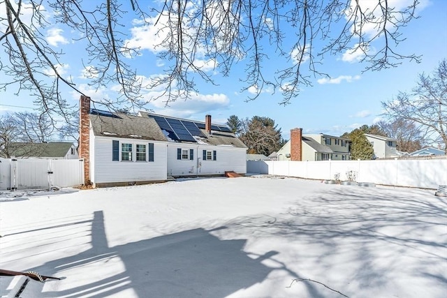 snow covered back of property with solar panels