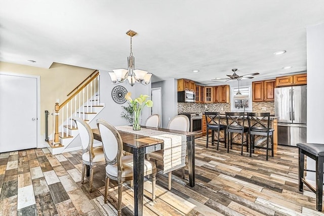 dining space featuring ceiling fan with notable chandelier and light hardwood / wood-style flooring