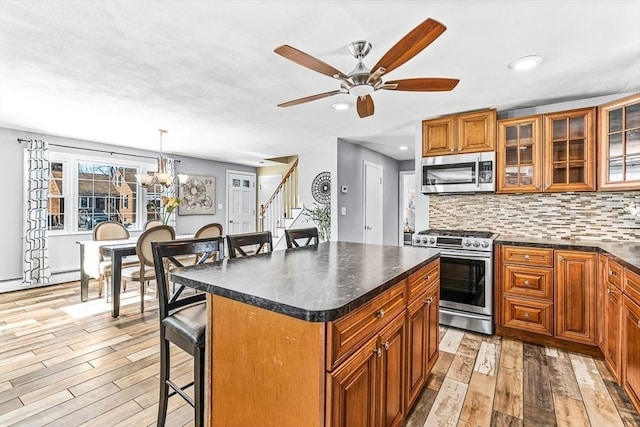 kitchen with appliances with stainless steel finishes, pendant lighting, a breakfast bar area, a center island, and light hardwood / wood-style floors