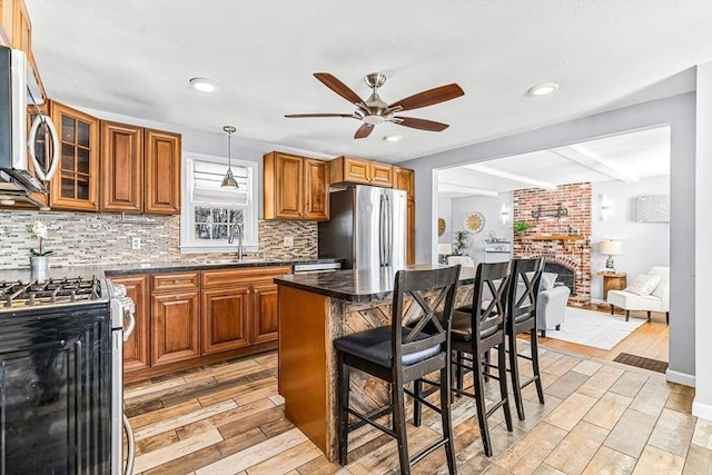 kitchen with a breakfast bar, sink, decorative light fixtures, a center island, and appliances with stainless steel finishes