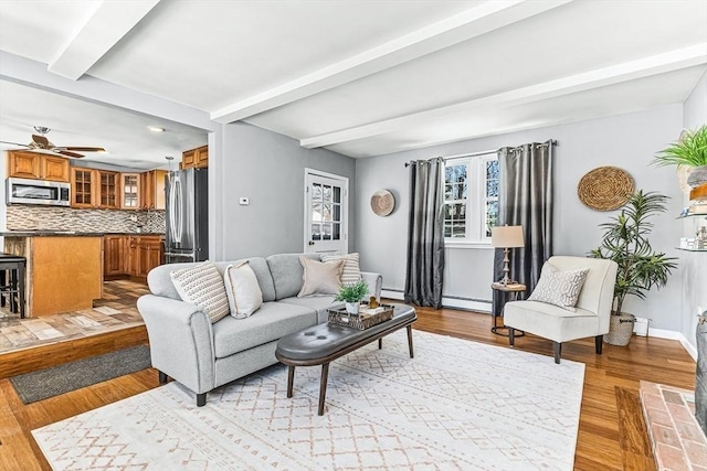 living room with beamed ceiling, ceiling fan, a baseboard radiator, and light wood-type flooring