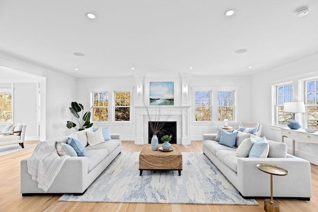 living area featuring a high end fireplace, crown molding, recessed lighting, and wood finished floors