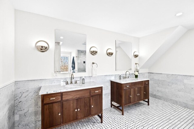 full bath with a sink, a wainscoted wall, and tile walls