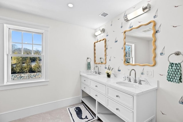 bathroom featuring visible vents, a sink, baseboards, and double vanity