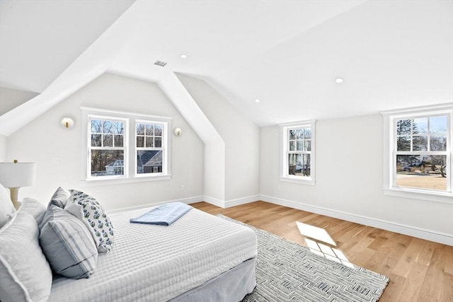 bedroom featuring lofted ceiling, wood finished floors, visible vents, and baseboards