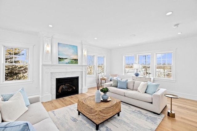 living room featuring recessed lighting, plenty of natural light, a fireplace, and light wood-style floors