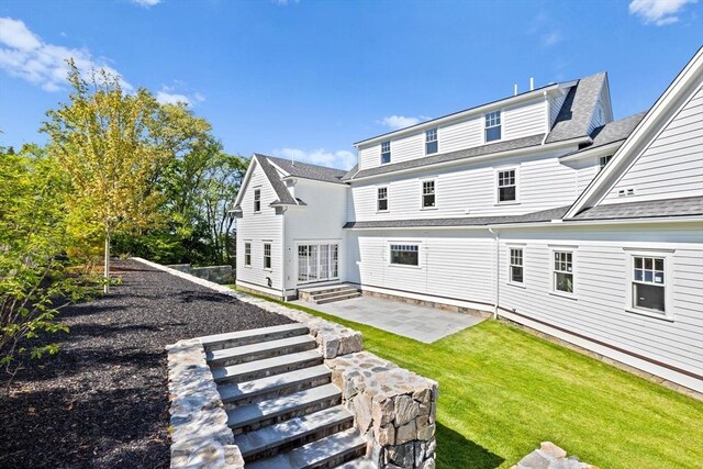 back of house featuring a shingled roof, a lawn, and a patio