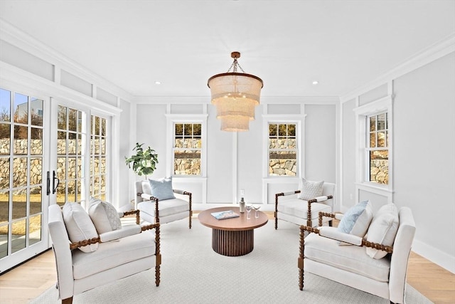 living area with ornamental molding, a notable chandelier, and a decorative wall