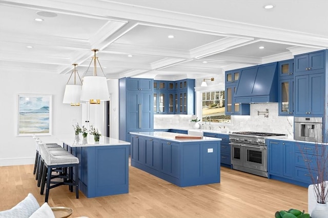 kitchen featuring stainless steel appliances, premium range hood, blue cabinetry, and a kitchen island