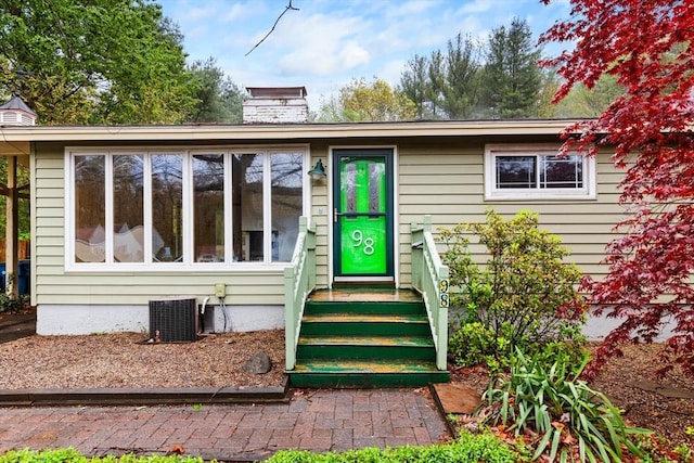 doorway to property with cooling unit and a chimney
